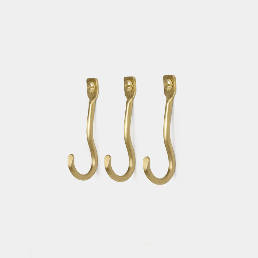 Ferm Living Curvature Hooks Set of 3 in Brass — hand-formed solid brass wall hooks with sculptural organic shapes.