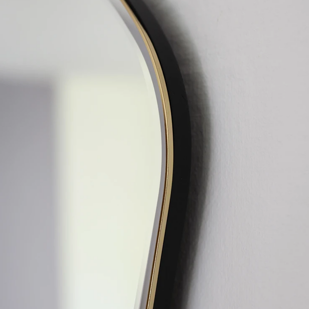 Close-up of Pond Mirror Large in brass showing polished frame and softly curved edge.