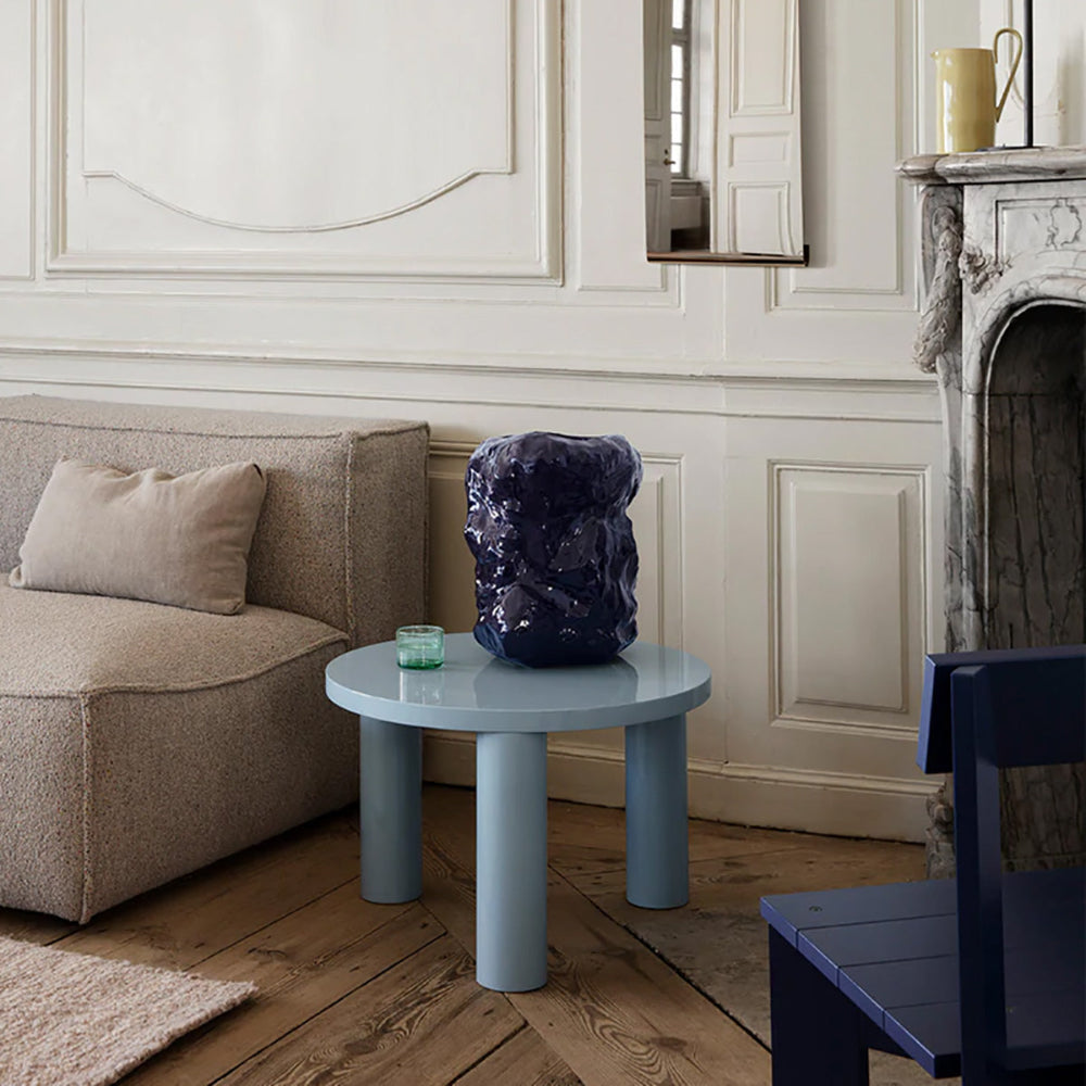 Post Table Small in Ice Blue styled in a modern living room with sofa and rug.