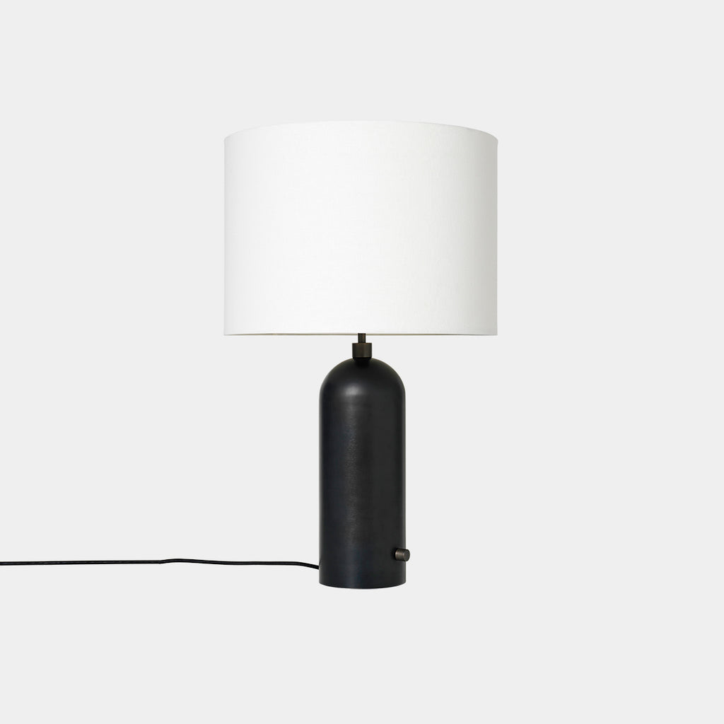 Gravity Table Lamp in Blackened Steel with White Fabric shade on neutral background